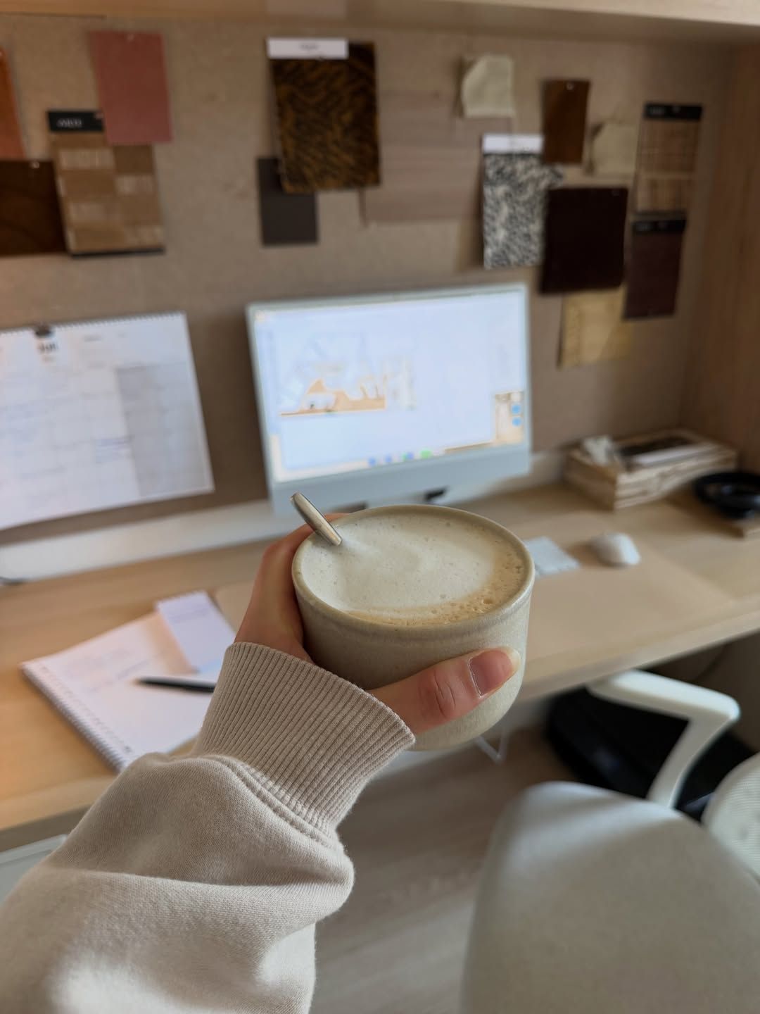 Cup of coffee on a desk with a moodboard behind it