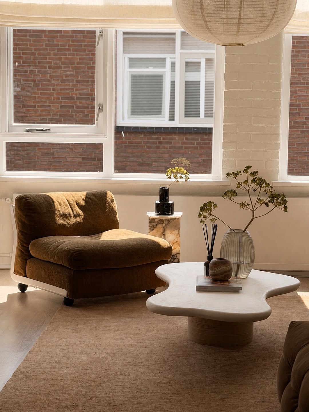 Zina's living room with an organic white coffee table, lounge chair and dried branches