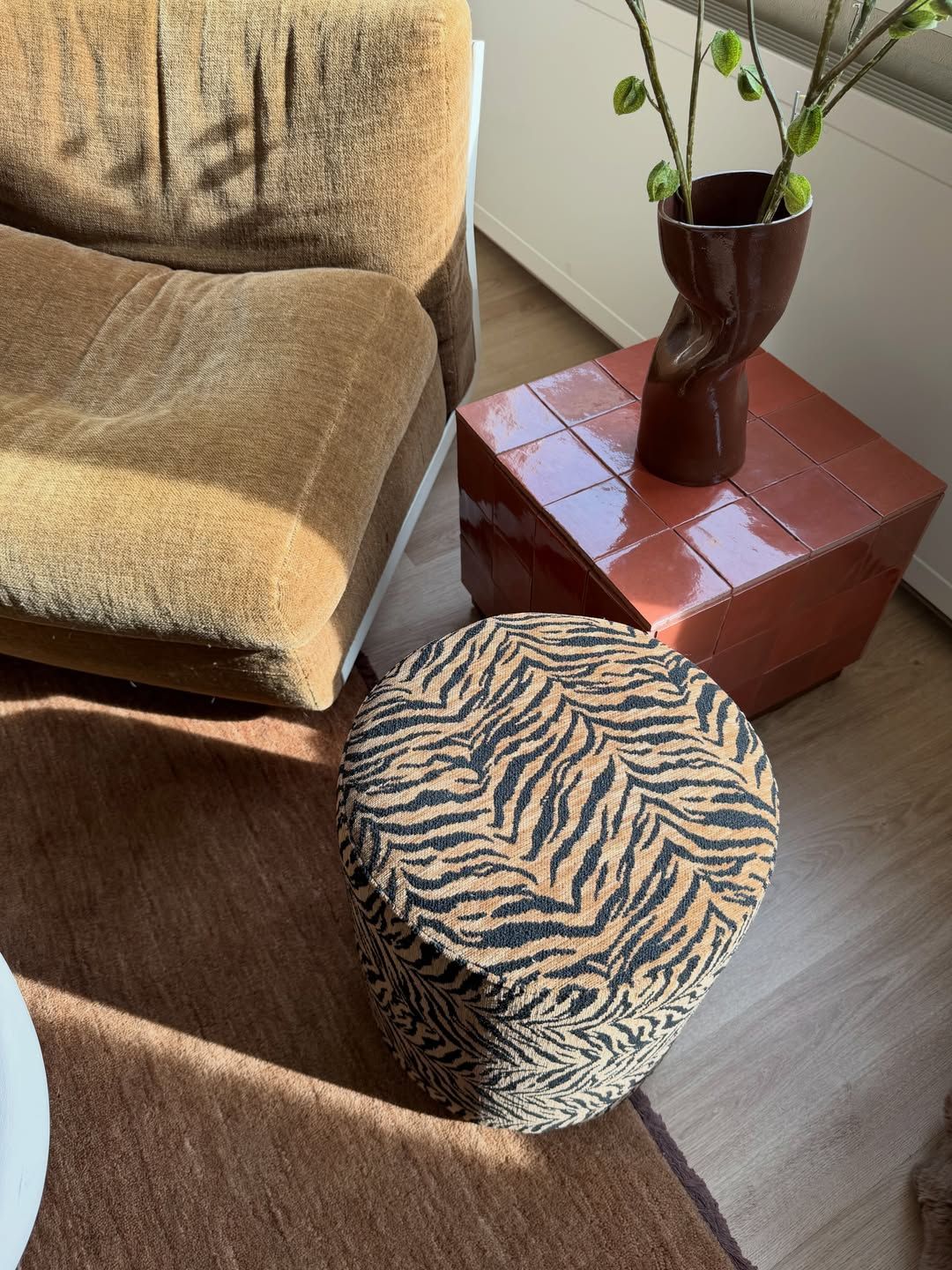 Tiger print pouf, terracotta side table and a sculptural vase